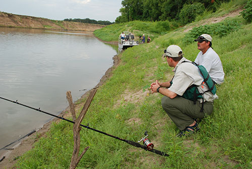 anglers on riverbank with rod and reel