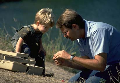 Small boy and man study tackle box