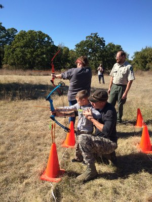 Family learning archery with a park ranger in the background