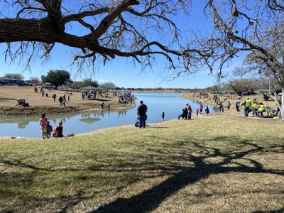 Kids and their families fishing around a cove at Kid Fish 2022.