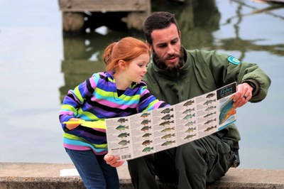 Ranger shows little girl a brochure that shows different types of fish
