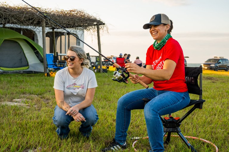 Young adult woman learning to cast a fishing rod and reel