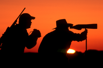 hunters using spotting scope looking for game as the sun sets