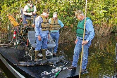 Alligator huntors with alligator on boat