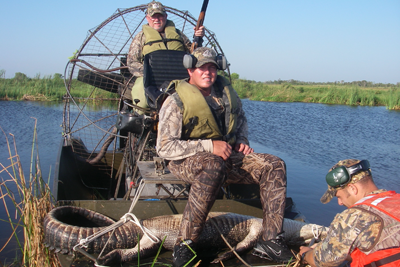 Hunters pose on air boat with harvested alligator