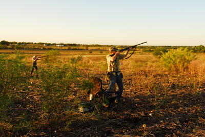 Hunter in a field aiming firearm