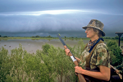 Hunter on prairie watching storm in distance