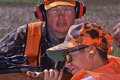 Adult instructing young hunter on shooting