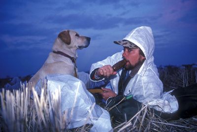 Goose hunter calling geese with dog