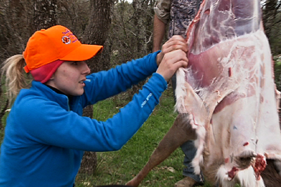 woman skinning hanging deer