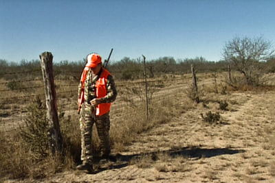 Hunter walks along fence line