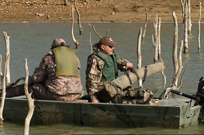hunters in boat with guns in cases