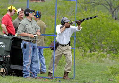 shooter takes aim with shotgun as Gov. Perry looks on
