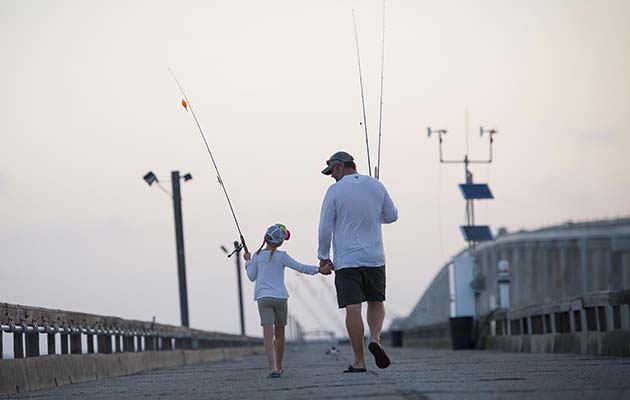 father and child anglers walking along a bridge