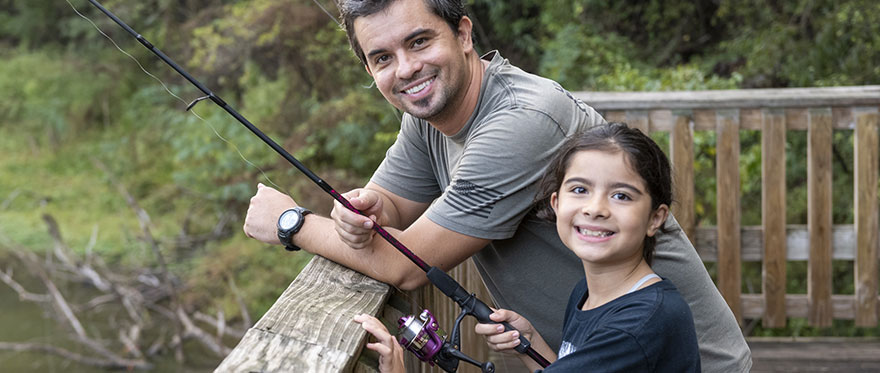father and child anglers pose on pier