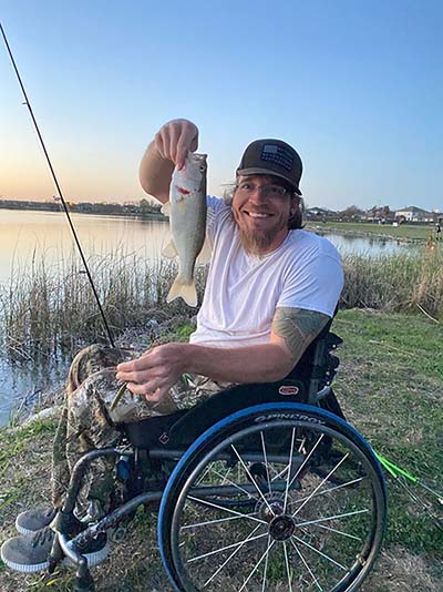 man in wheelcair with fishing rod and fish