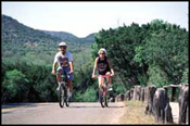 Image of a man and a woman enjoying a bicycle ride along a hill country road
