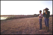 Image of two ranchers with binoculars surveying the surrounding hillside
