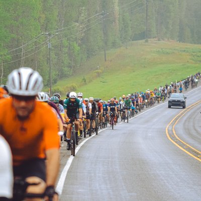 A large group of cyclists ride in the shoulder of a highway