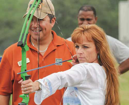 Man teaching woman archery shooting