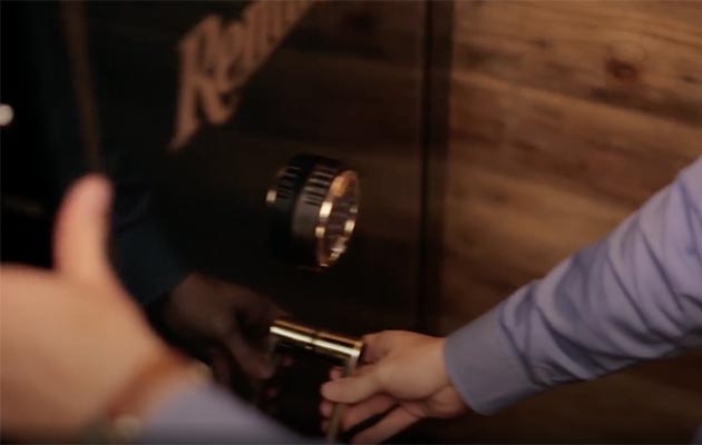 A gun owner securely locking his firearms safe.