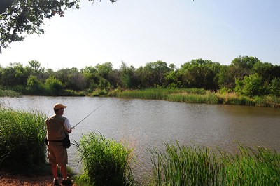 Man fishing from the bank of a waterway.