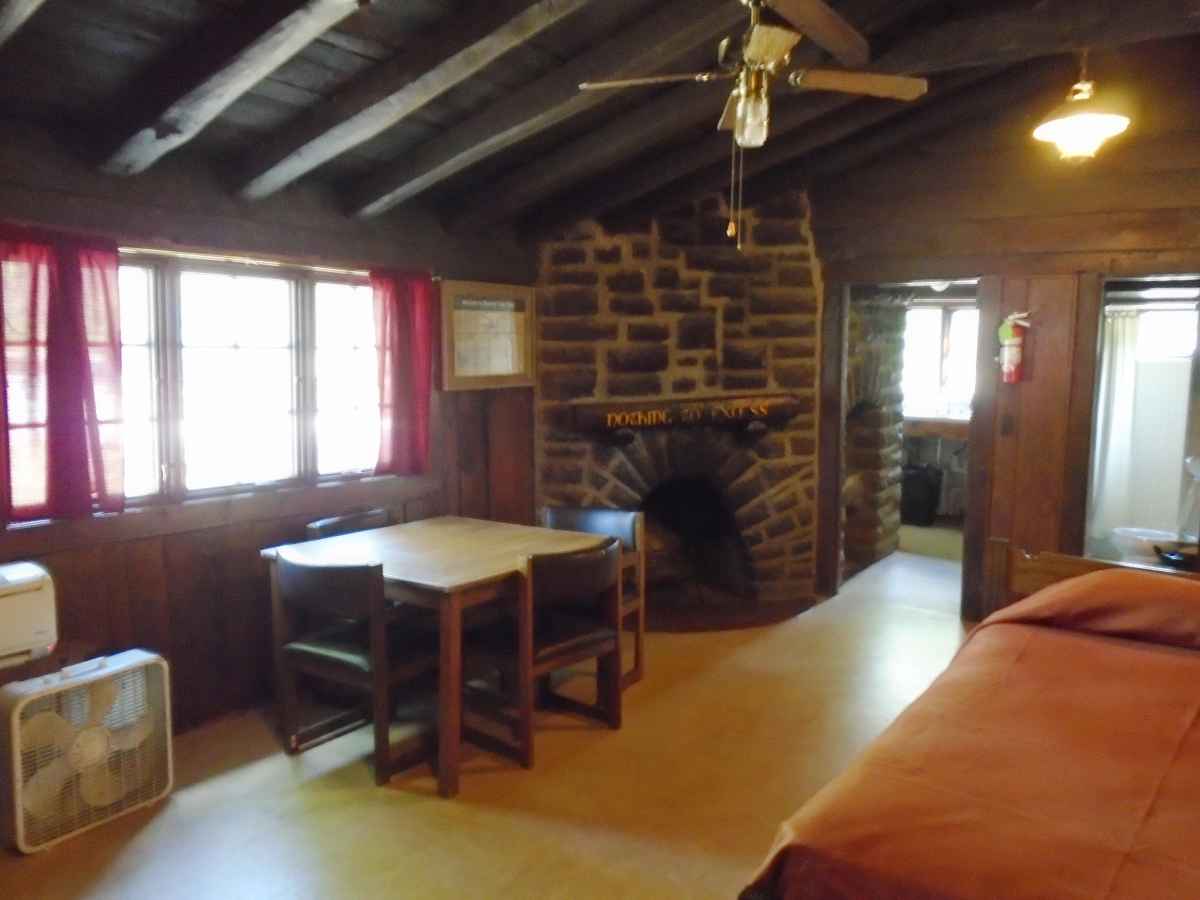 The living area of Cabin 6 has a single bed, fireplace and a table with chairs. 
