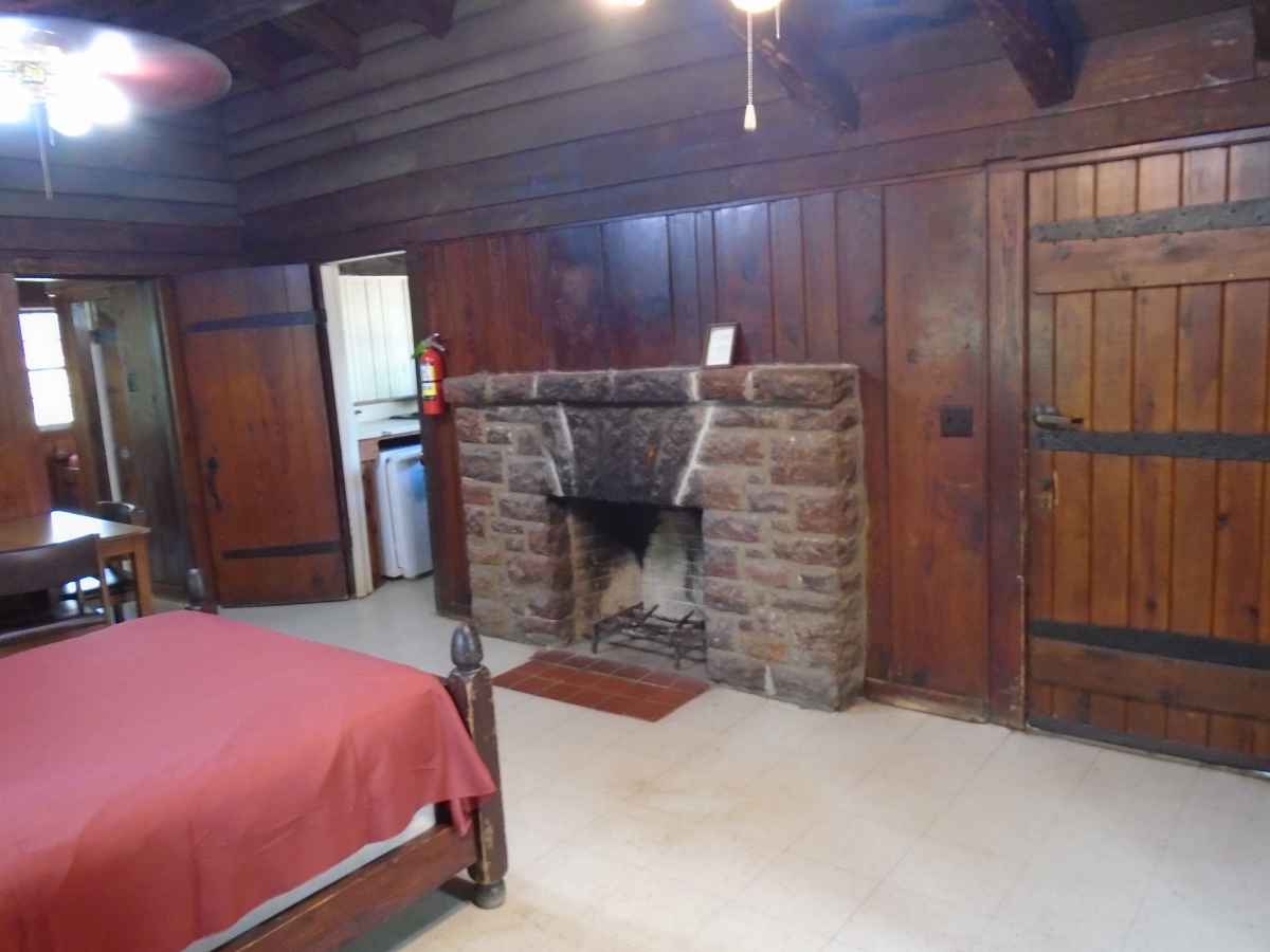 The living area of Cabin 7 has a double bed, a table with chairs and a fireplace.