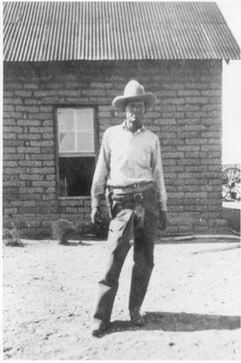 Black & white photo of a rancher in front of buildings