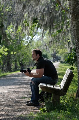 Guy sitting on bench holding camera