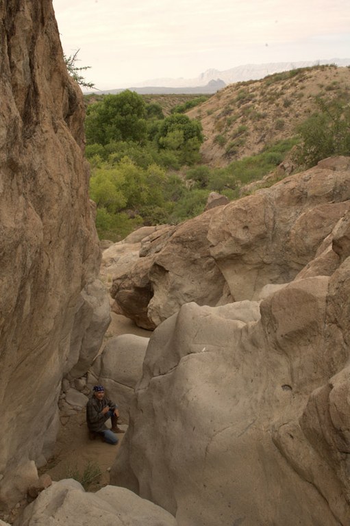 Looking down into rock crevice with mountains in the distance.