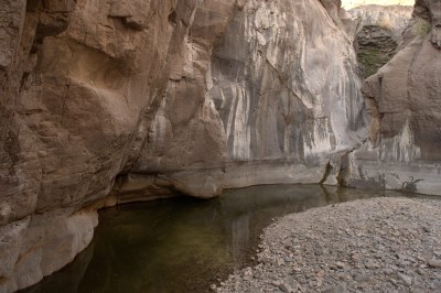 Creek curving underneath carved-out cliffs.
