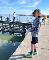 Boy holds fishing pole on the bank of the lake