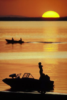 Fisherman on the lake backlit by a sunset.