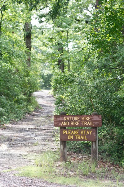 Trail into the woods with sign: Nature hike and bike trail. Please stay on trail"