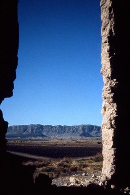 View through a window hole at the rocky ridge in the distance. 