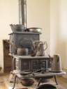 Antique cookstove with assorted pots sitting on it.