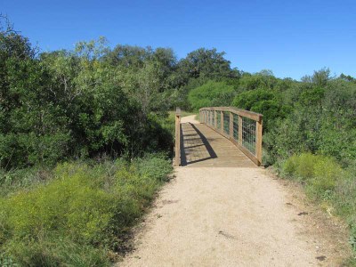 Packed surface trail leading to wooden bridge and beyond.