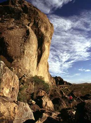 Hiker crossing rocky cliff base