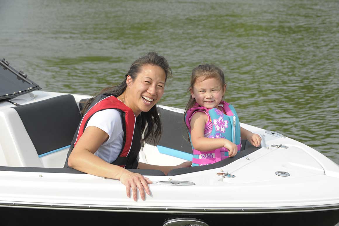 Mom and daughter wearing life jackets on boat