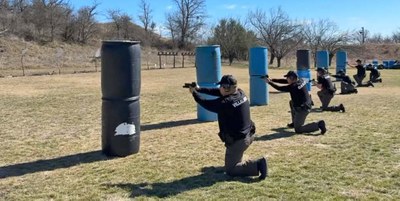 Shooting Range Person fires a rifle as an instructor follows nearby.