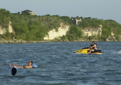 People swimming and using a jet ski in the lake.