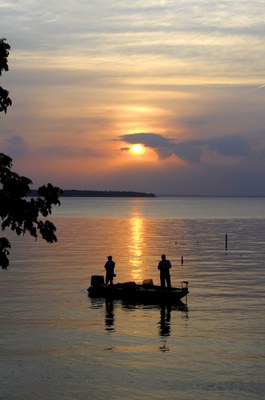 Fishermen in boat in silhouette at sunset.