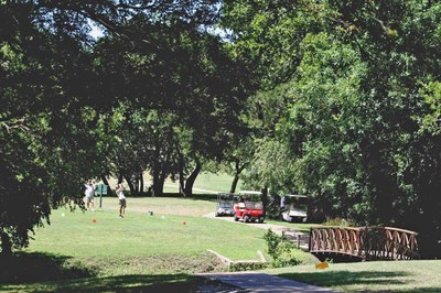 Golfer at end of swing, with creek in the foreground