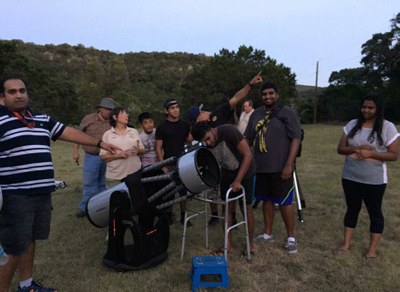 Group of people gathered around telescope
