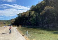 Mom takes photo of child against the backdrop of a green hillside
