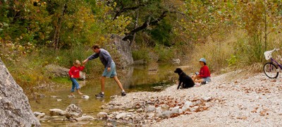 father assisting child cross water