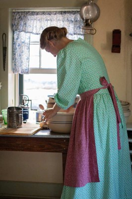 Woman in period clothing kneading bread