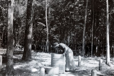 Man drinking from historic concrete drinking fountain in the woods