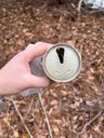 hand holding an empty drink can and some plastic trash